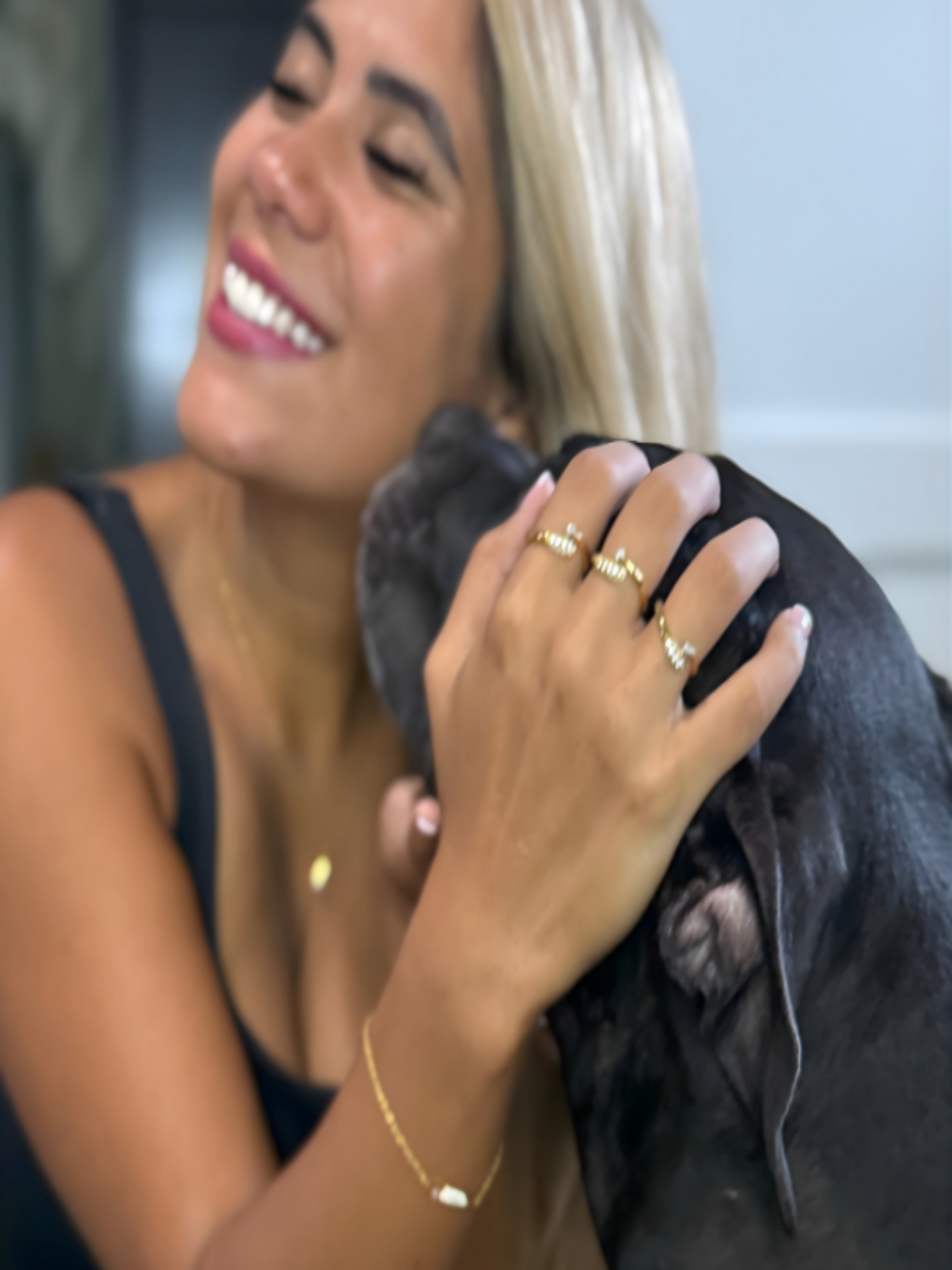 Gold stacking rings worn by a woman with a black dog, showcasing elegance and pet affection.